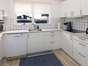 A modern kitchen with white cabinets, a Bosch dishwasher, a window with blinds, and a tiled backsplash. - 8 Person Holiday Home in Hadsund (Hadsund)