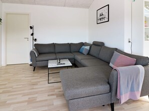 A modern living room with a grey sectional sofa, a small white coffee table, and a framed picture on the wall.