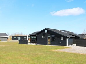 A modern black building with a sloped roof, a satellite dish, and a small porch area. - 8 Person Holiday Home in Hadsund (Hadsund)