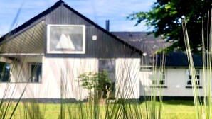 Une maison avec un toit en pente et une grande fenêtre.