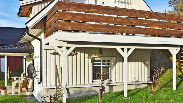 A white building with a sloped roof and wooden beams. - 4 Person Holiday Home in Oksvoll (Orland)