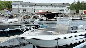 A marina with several boats docked, a building with a grey roof, and a rocky shoreline. - 4 Person Holiday Home in Oksvoll (Orland)