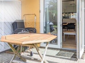 A wooden table with wheels, a chair, and a glass door leading to a room with a table and chairs. - 4 Person Holiday Home in Hals (Hals)