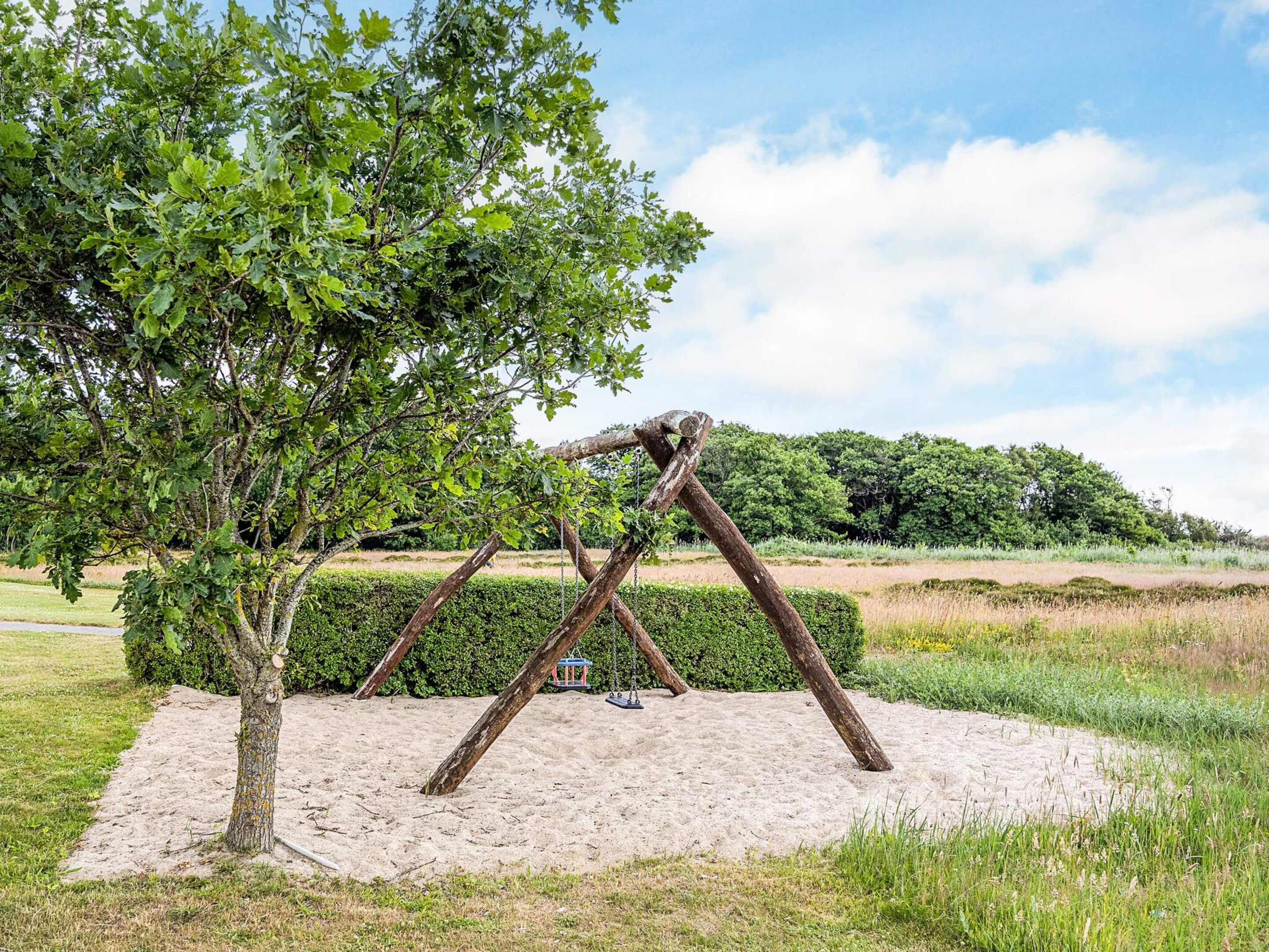 Een schommel in een park, met een boom ernaast.