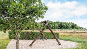 Columpios en un parque con un árbol cercano.