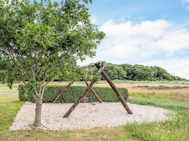 Columpios en un parque con un árbol cercano.