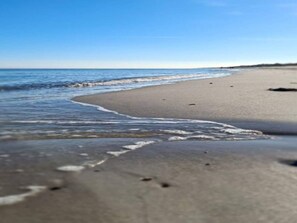 A beach with gentle waves and a clear sky.