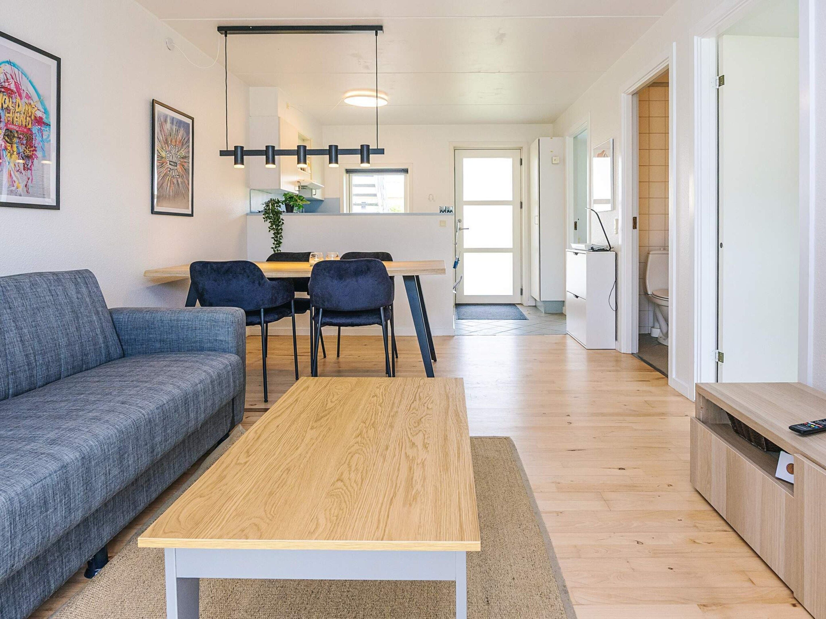 Una sala moderna con un sofá, una mesa de centro y un comedor con sillas y una mesa.