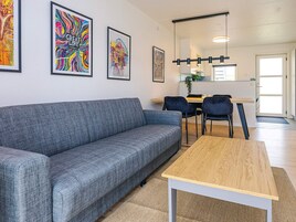 A modern living room with a grey sofa, a wooden coffee table, and colorful artwork on the walls.