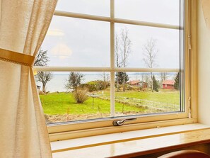 Una ventana con vista a un área con césped, árboles y casas.