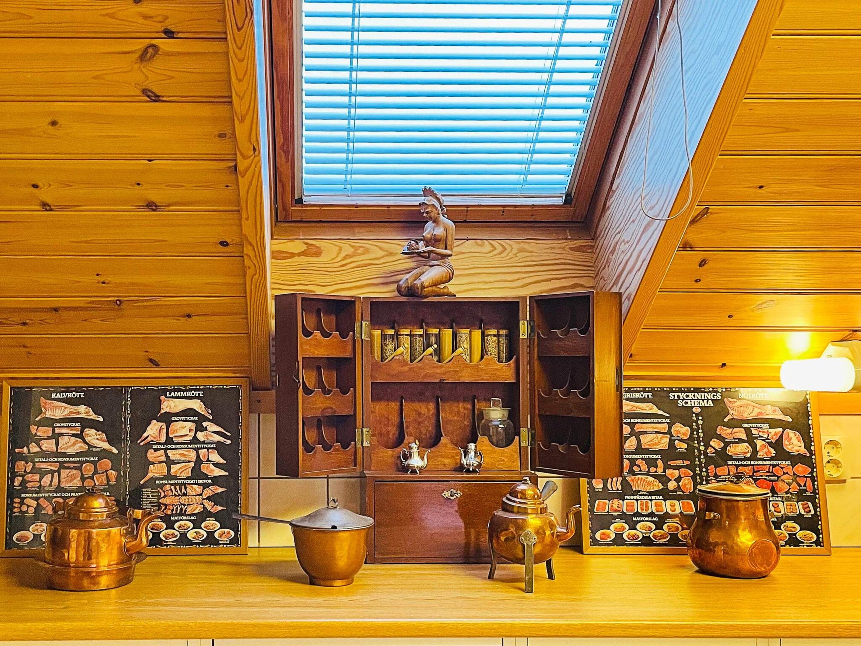 A wooden interior with a skylight, a shelf with kitchen utensils, and a decorative figure.