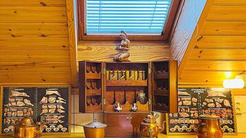 A wooden interior with a skylight, a shelf with kitchen utensils, and a decorative figure.