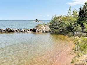 Paisaje costero con agua cristalina, un litoral rocoso y vegetación densa.