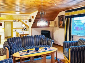 A cozy living room with striped sofas, a wooden ceiling, and a view of a house through a window. - 8 Person Holiday Home in Bralanda (Bralanda)