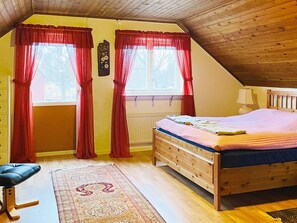 A bedroom with a wooden bed, red curtains, a bedside lamp, and a patterned rug. - 8 Person Holiday Home in Bralanda (Bralanda)