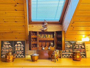 Puisesti sisustettu tila, jossa on kattovalokuvio, hylly keittiötarvikkeille ja seinälle kiinnitetty ruokalista.