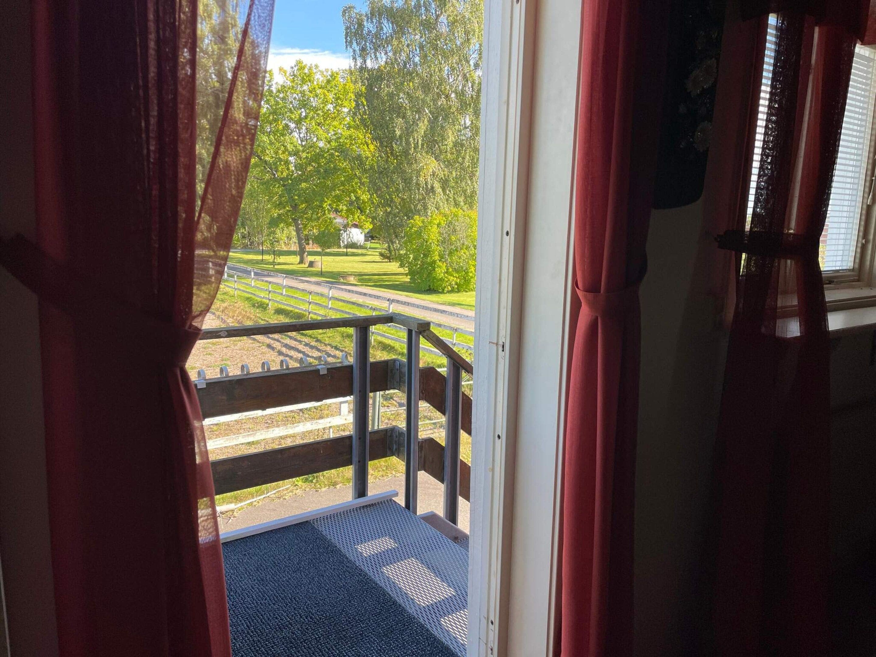 A view from a room with a window, a metal railing, and a door.
