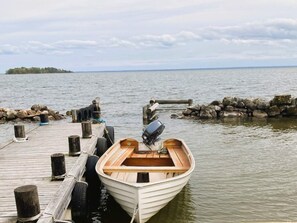 A small wooden boat docked at a wooden pier with a rocky breakwater in the background. - 8 Person Holiday Home in Bralanda (Bralanda)