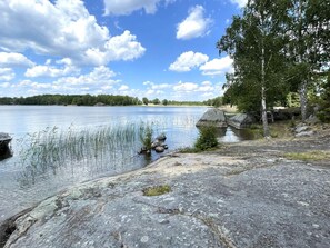 Blick auf einen See mit ruhigem Wasser, Felsen und Bäumen.
