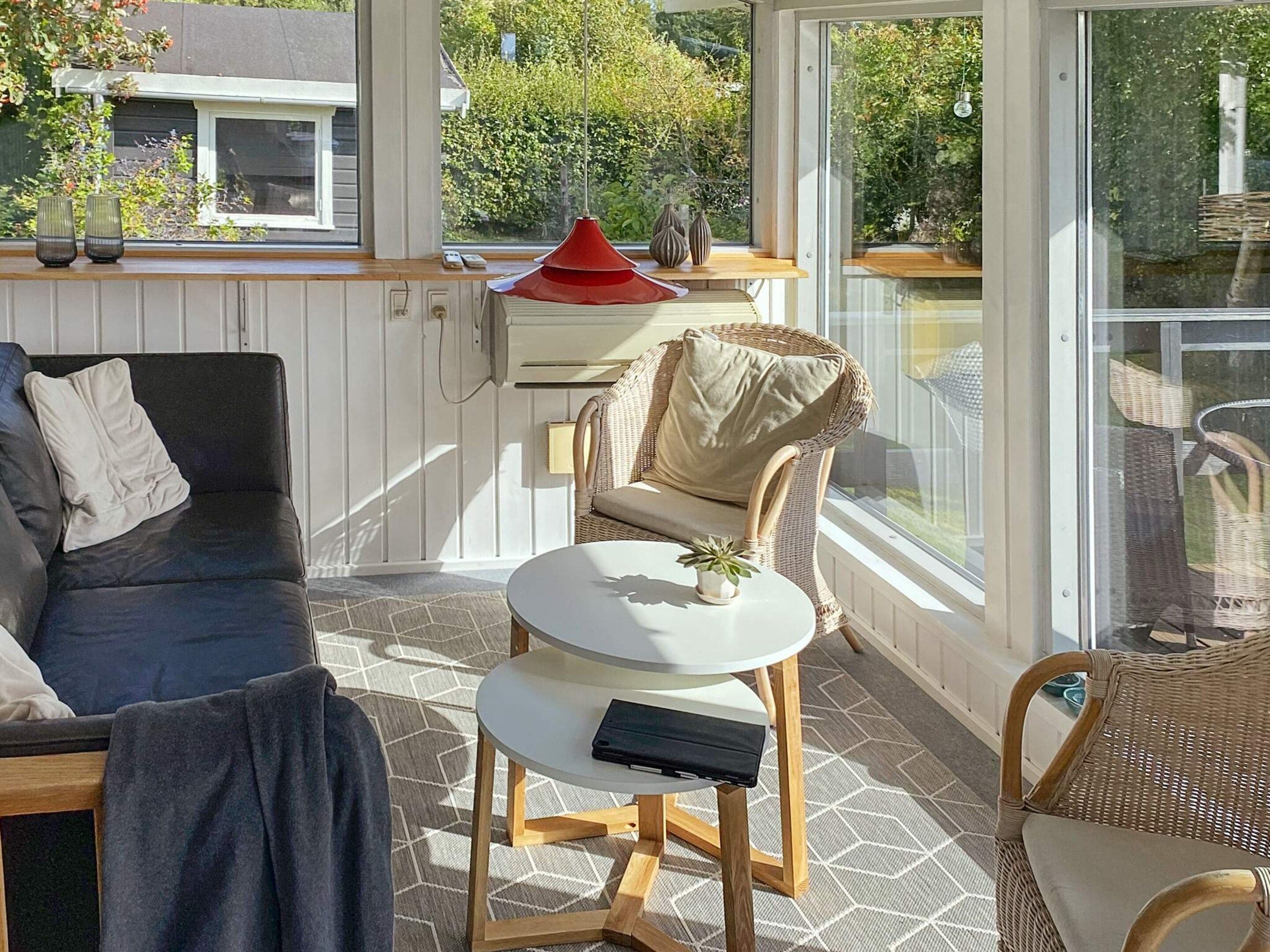 A modern living room with a sofa, a round table, and a wicker chair.