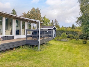 A modern house with a deck, large windows, and a garden.