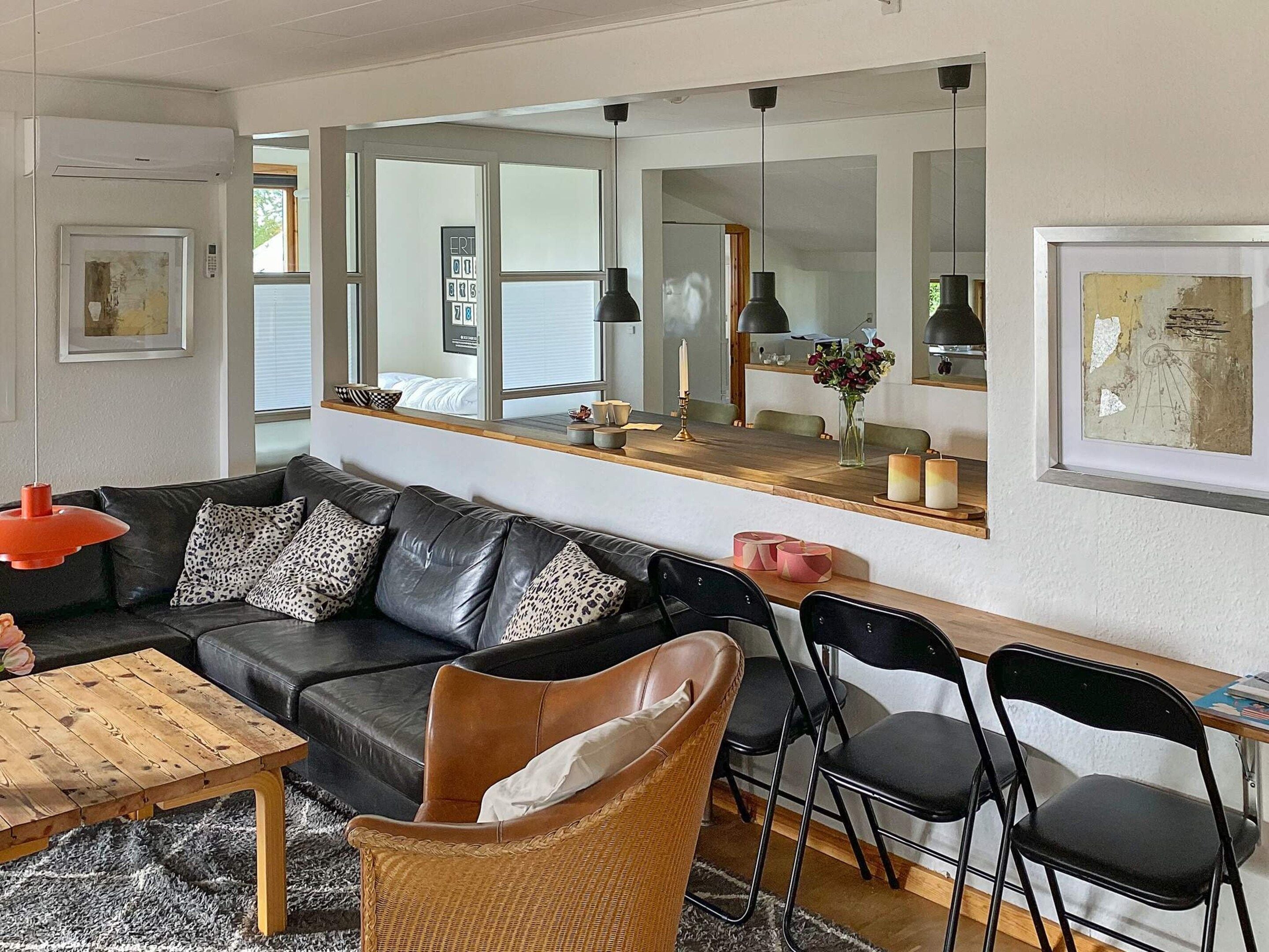 A modern living room with a black leather sofa, a wooden coffee table, and a wicker chair.