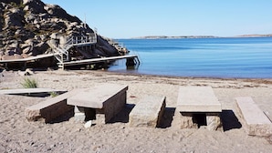 Une plage rocheuse avec une jetée et des bancs en pierre.