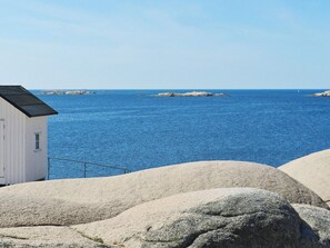 A coastal scene with a white building, large rocks, and calm blue sea. - 4 Person Holiday Home in Lysekil-by Traum (Lysekil)