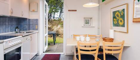 A modern kitchen with a dining area, featuring a stove, sink, and a table with chairs.