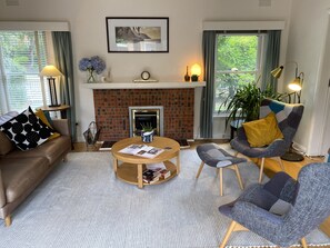 A living room with a brick fireplace, a round coffee table, a sofa, and a modern armchair. - Spacious and comfortable home in fantastic area (Beaumaris)