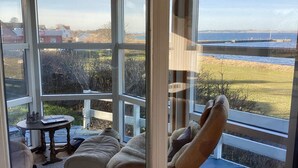 A cozy room with a large window overlooking a scenic view of the sea and a grassy landscape. - 4 Person Holiday Home in Knebel (Knebel)