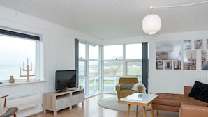 A spacious living room with a television, a sofa, a chair, and a coffee table. - 4 Person Holiday Home in Knebel (Knebel)