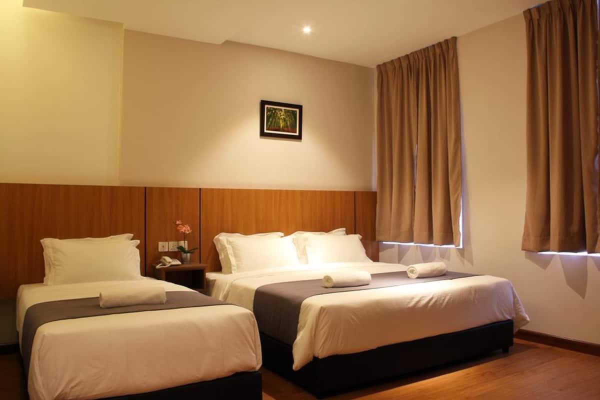 A hotel room with two beds, wooden headboards, a nightstand with a lamp, and a framed picture on the wall.