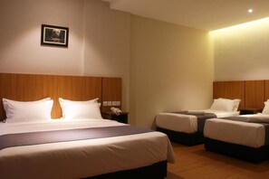 A hotel room with a large bed, two smaller beds, wooden headboards, a bedside telephone, and a framed picture on the wall. - Ahyu Hotel (Kuala Lumpur)