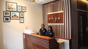 A reception desk with framed pictures on the wall, a wooden reception desk, and a sign with the name 'ahyu'. - Ahyu Hotel (Kuala Lumpur)