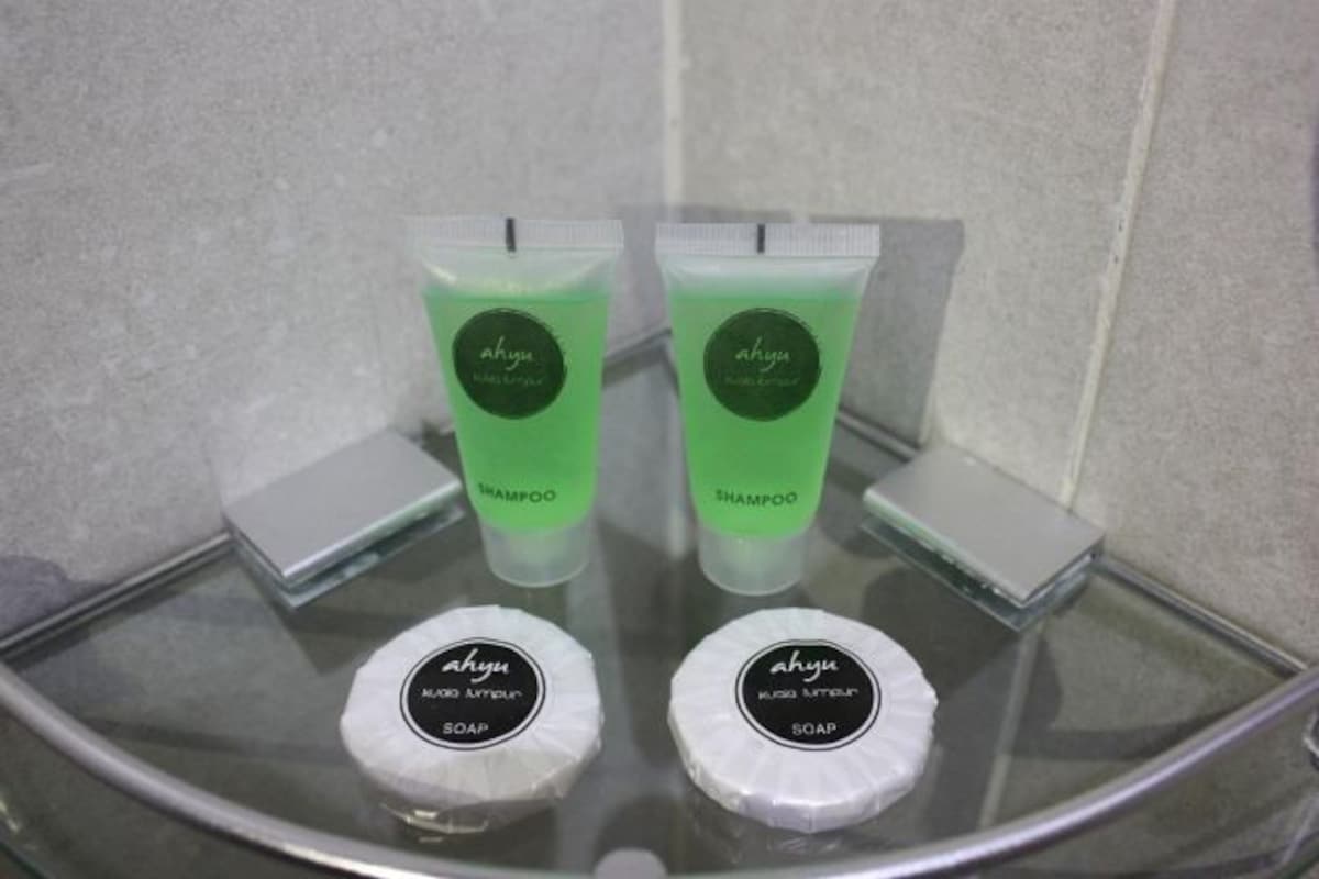 A bathroom with two green shampoo bottles and two white soap bars on a glass shelf.