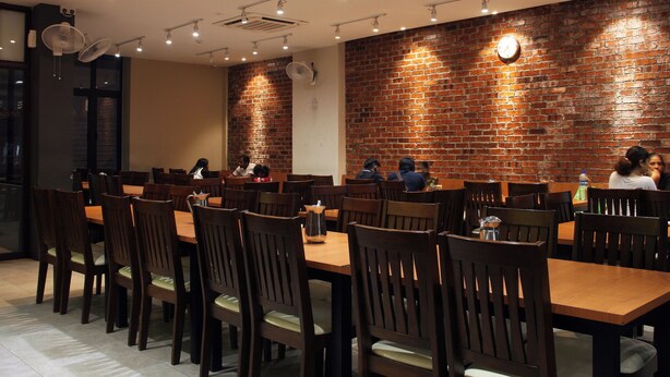 A restaurant with brick walls, wooden tables, and chairs. - Ahyu Hotel (Kuala Lumpur)