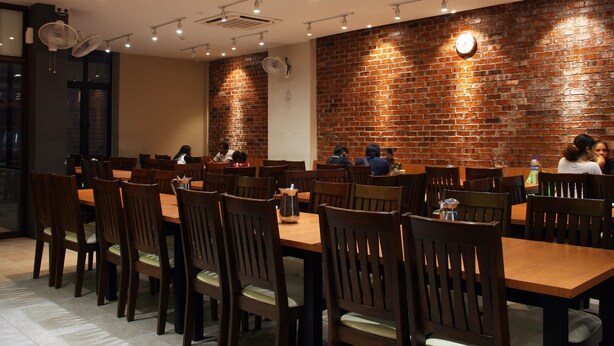 A dining area with brick walls, wooden tables, and chairs. - Ahyu Hotel (Kuala Lumpur)