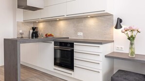 A modern kitchen with white cabinetry, a built-in oven, and a coffee maker.