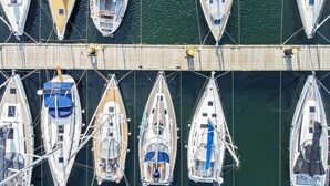 A marina with multiple sailboats docked at a wooden pier.