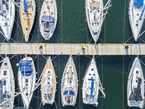Un port de plaisance où sont amarrés plusieurs voiliers, le long d’une jetée en bois.