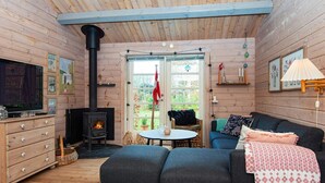 Une pièce chaleureuse avec une cheminée, un canapé, une télévision et une table à manger.