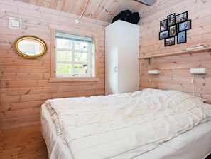 Quarto com cama, janela, espelho e prateleira na parede com quadros.