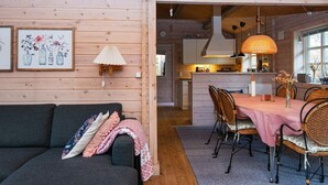 Un intérieur chaleureux avec un canapé, une table à manger, des chaises en osier et un coin cuisine.