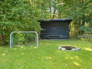 A fenced area with a bench and a small shed in a wooded setting. - 4 Person Holiday Home in Glesborg (Glesborg)