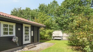 Une maison avec un petit jardin devant, un espace extérieur aménagé et couvert, et un garage.