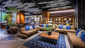 A modern lounge area with sofas, a coffee bar, and a bookshelf. - &Here TOKYO UENO (Tokyo)