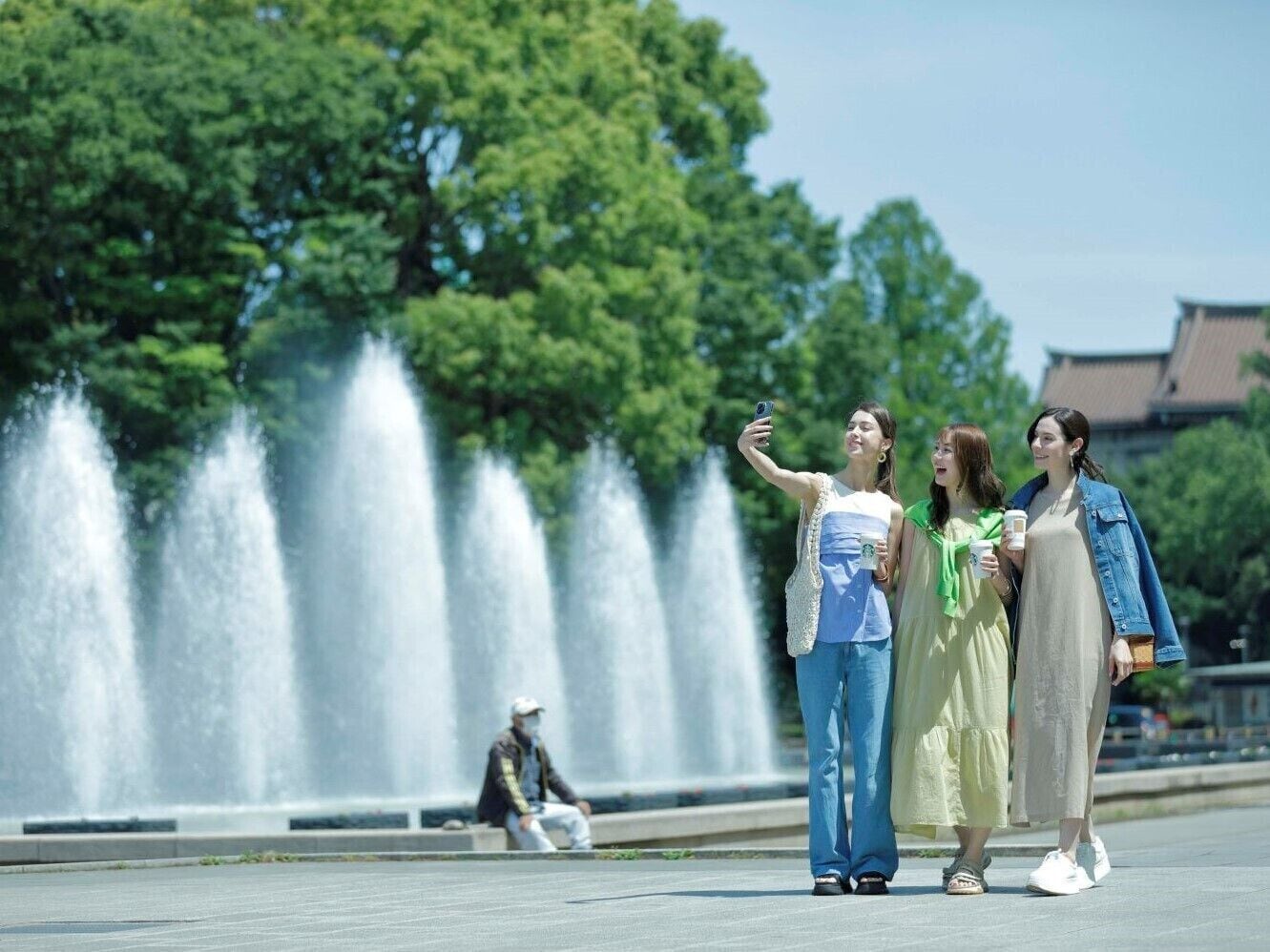 A group of people taking a selfie in front of a fountain with a traditional building in the background.