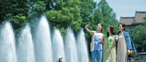 A group of people taking a selfie in front of a fountain with a traditional building in the background.