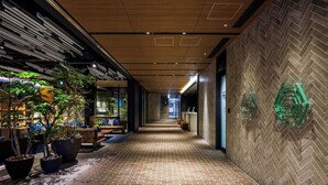A corridor with a brick floor, wooden ceiling panels, and a herringbone-patterned wall. - &Here TOKYO UENO (Tokyo)